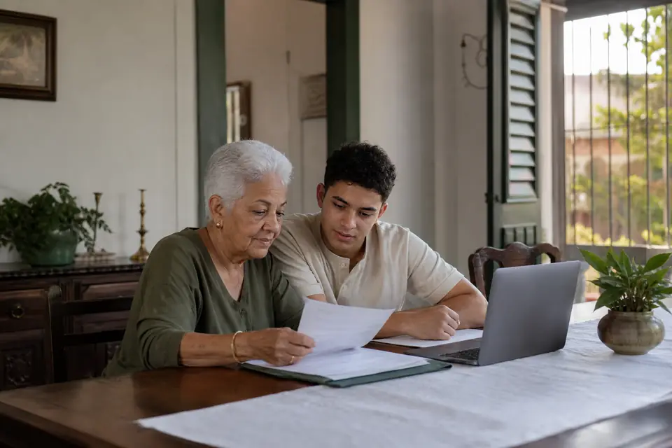 Señora mayor y su nieto completan formularios en la computadora en el comedor